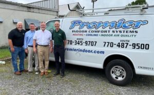 A team of HVAC technicians standing proudly in front of a Premier Indoor Comfort Systems van for Leap Partners in Greensboro, NC.