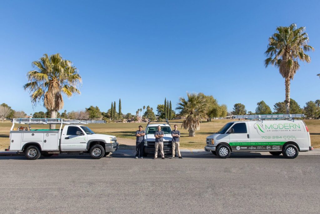 Modern Air Conditioning & Heating team standing between their service vehicles in Boulder City, NV.