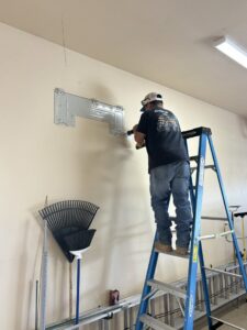 An HVAC technician installing a mini-split mounting bracket for Buddy's Refrigeration LLC in Mesquite, NV.
