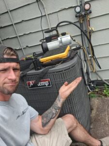 An HVAC technician performing maintenance on an outdoor AC unit with a vacuum pump for Recovery HVAC in Smyrna, TN.