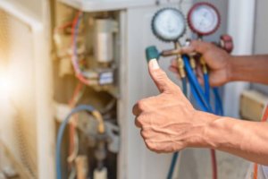 An HVAC technician giving a thumbs-up while performing AC repair with gauges at Team Mechanical, Inc in Minneapolis, MN.