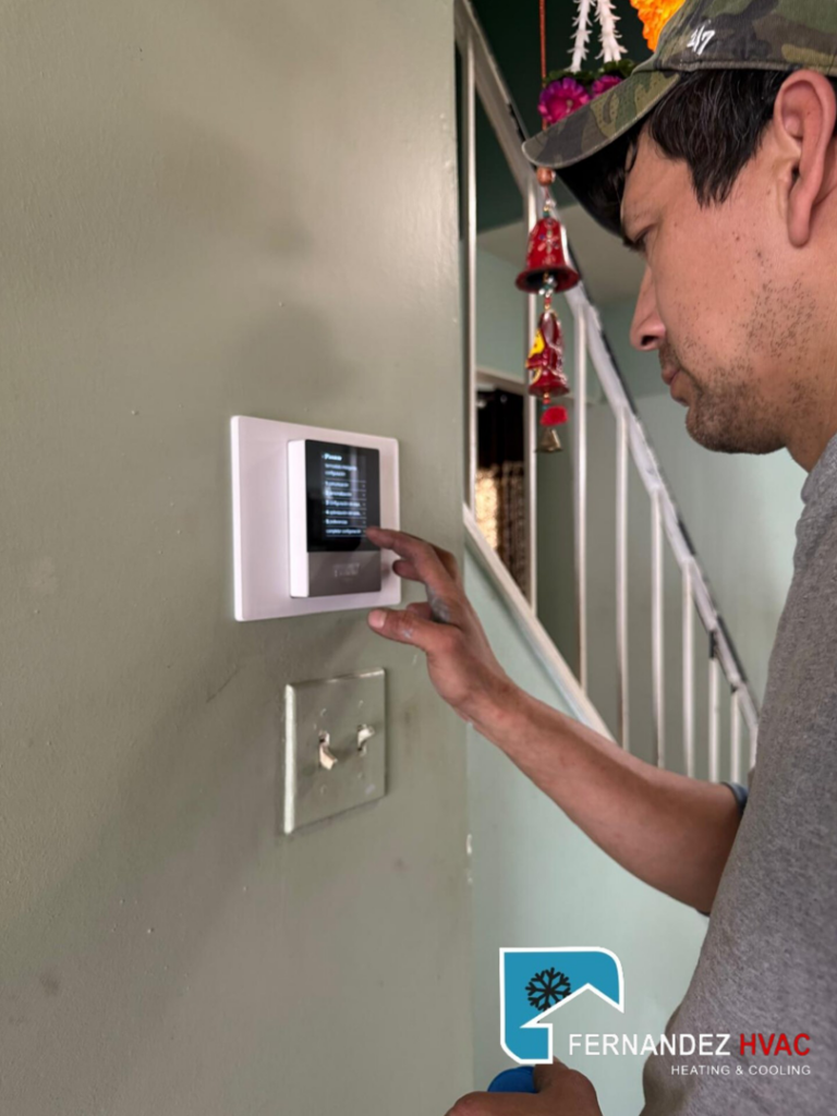 An HVAC technician from Fernandez HVAC adjusting a smart thermostat in Alexandria, VA.