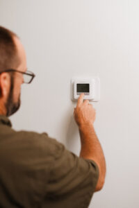 An HVAC technician adjusting a digital thermostat on a wall for Grace Heating & Air in Clarksville, TN.