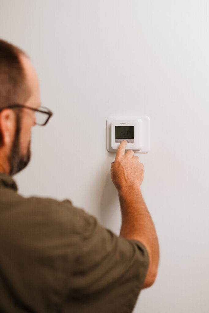 An HVAC technician adjusting a digital thermostat on a wall for Grace Heating & Air in Clarksville, TN.