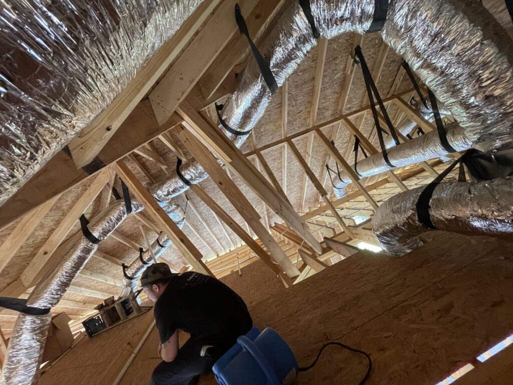 An HVAC technician working on ductwork in an attic for Caballero's A/C & Heating in Marrero, LA.