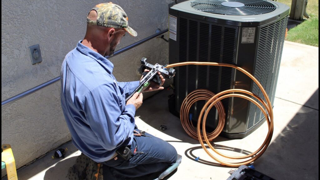 An HVAC technician bending copper refrigerant lines next to an outdoor unit for Controlled Climates Heating and Air Conditioning, Inc. in Fresno, CA.