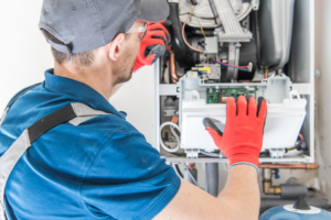 An HVAC technician performing maintenance or repair on a boiler system for Basic HVAC in Indianapolis, IN.