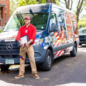 A Jump HVAC technician standing proudly with a branded service van and tools in Lakewood, CO.