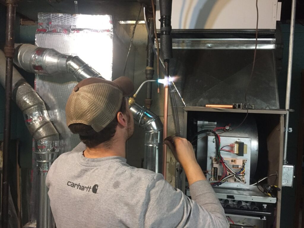 An HVAC technician brazing copper lines on an indoor furnace unit for Fellowship Heating and Cooling in Indianapolis, IN.