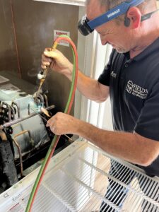 An HVAC technician brazing copper lines on an indoor unit for Fields Cooling Heating & Refrigeration in Foley, AL.