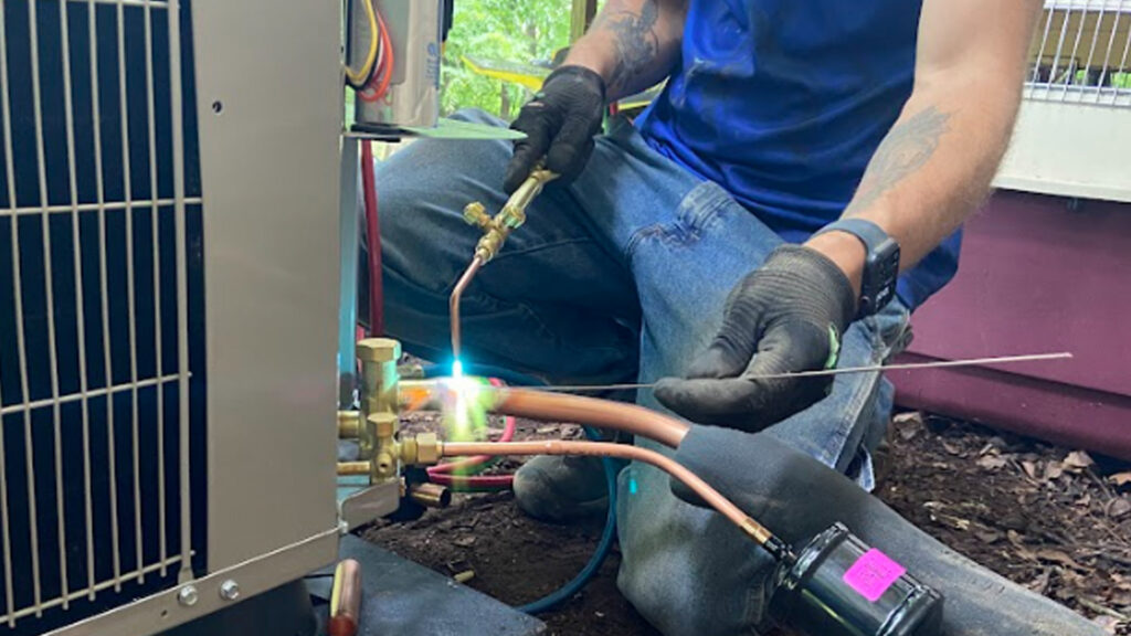 An HVAC technician from Top Notch Heating and Air Conditioning brazing copper lines on an outdoor unit in Bowling Green, KY.
