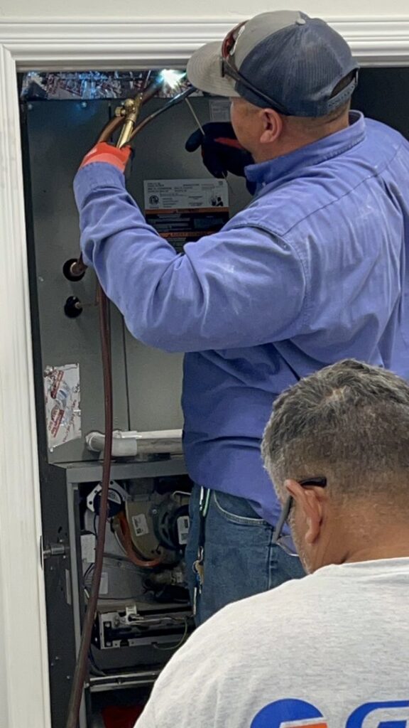 An HVAC technician brazing pipes on an indoor unit during an installation or repair by Bluestone Refrigeration LLC in Las Cruces, NM.