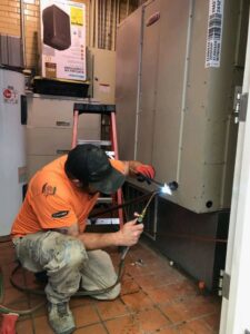 An HVAC technician from Greens Heating & Air Conditioning brazing copper pipes on an indoor HVAC unit, Douglasville, GA.
