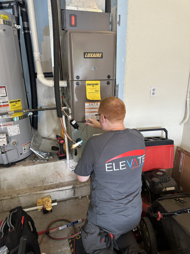 An HVAC technician brazing refrigerant lines on an indoor unit at Elevate Heating & Cooling in Hillsboro, OR.