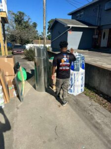 An HVAC technician wearing a branded shirt, carrying ductwork and insulation at a job site for Air Casablanca Heating & Cooling in Myrtle Beach, SC.