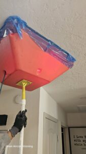 An HVAC technician from Alien Air Conditioning and Heating installing or servicing a ceiling-mounted unit in Phoenix, AZ.