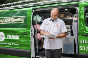 HVAC technician Chad from DFH Company Heating and Air Conditioning documenting a job next to his service van in Louisville, KY.