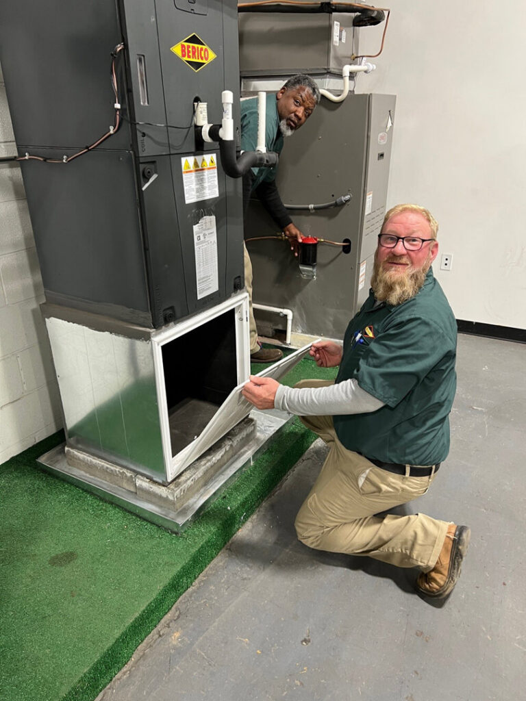 A Berico HVAC technician changing an air filter in an indoor heating and cooling unit in Greensboro, NC