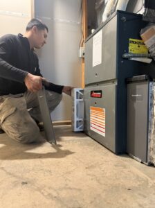 An HVAC technician from JCL Heating and Cooling LLC changing an air filter in a furnace in Gresham, OR.