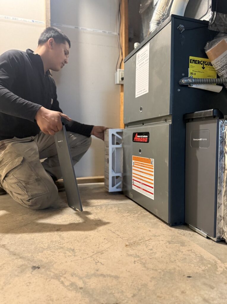 An HVAC technician from JCL Heating and Cooling LLC changing an air filter in a furnace in Gresham, OR.