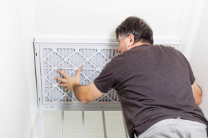 An HVAC technician changing an air filter, a service provided by TC Heating and Air Conditioning LLC in Elgin, IL.