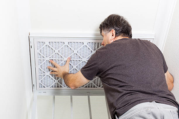 An HVAC technician changing an air filter, a service provided by TC Heating and Air Conditioning LLC in Elgin, IL.