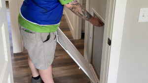 An HVAC technician from Top Notch Heating and Air Conditioning changing an air filter in a residential home in Bowling Green, KY.