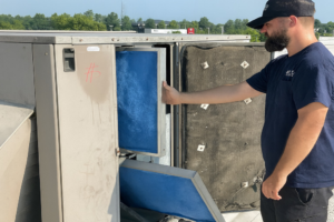 An HVAC technician changing air filters in a commercial rooftop unit for Hyland Filter Service in Owensboro, KY.
