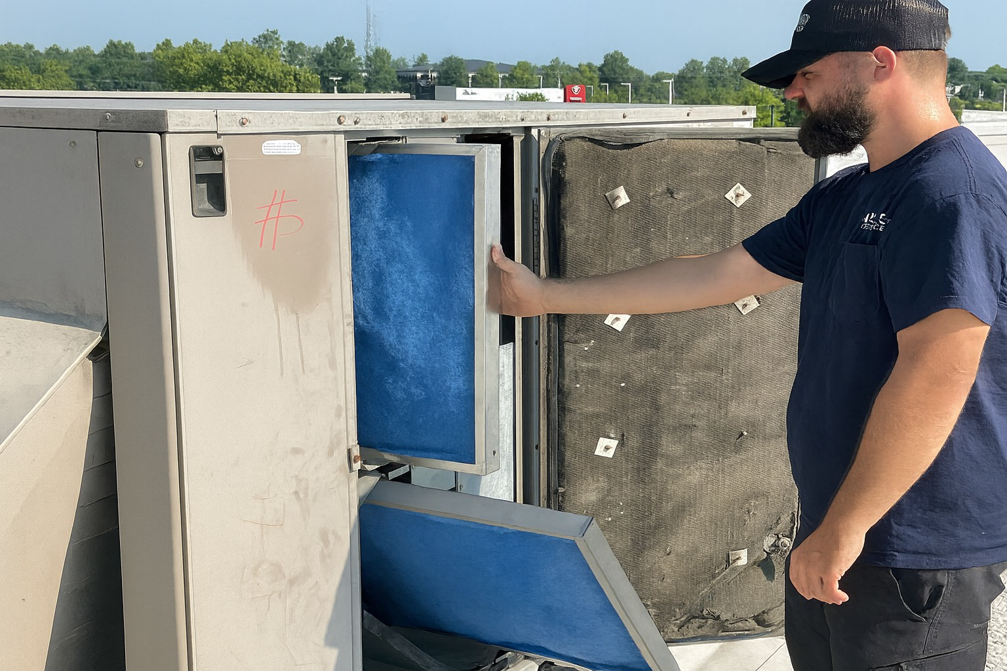 An HVAC technician changing air filters in a commercial rooftop unit for Hyland Filter Service in Owensboro, KY.