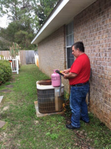 An HVAC technician charging an outdoor AC unit with refrigerant at 911 Heating and Air Conditioning Co.,Inc. in Mary Esther, FL