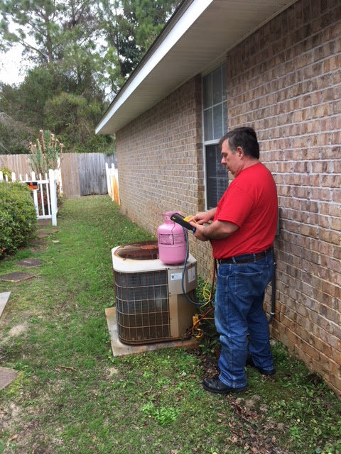 An HVAC technician charging an outdoor AC unit with refrigerant at 911 Heating and Air Conditioning Co.,Inc. in Mary Esther, FL