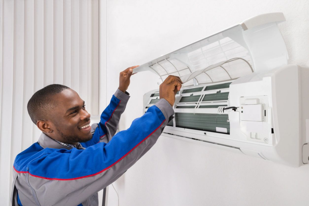A smiling HVAC technician from Iceman Cooling and Heating checking an AC filter in Baton Rouge, LA.
