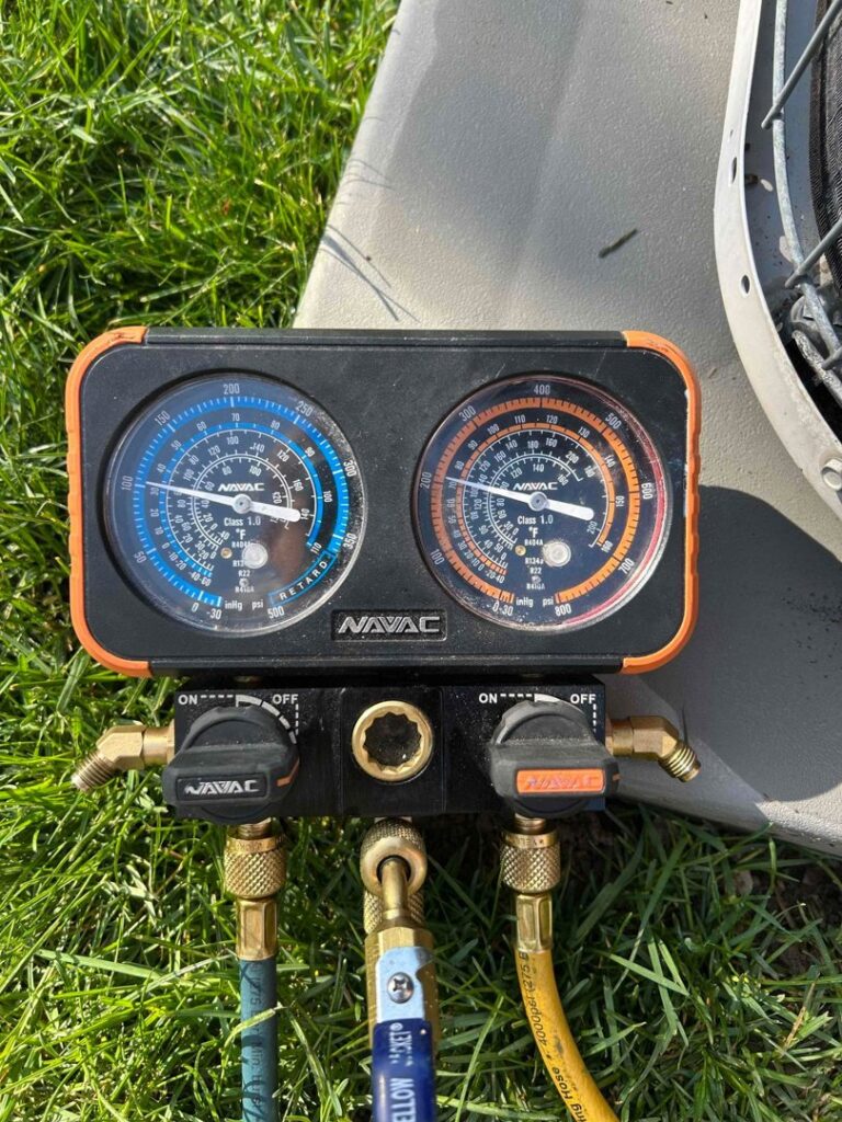 An HVAC technician using a traditional manifold gauge to check refrigerant levels on an outdoor AC unit in Orem, UT.
