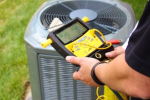 An HVAC technician checking refrigerant levels on an AC unit with a digital gauge for G.M. AIR Conditioning & Heating in Wichita, KS.