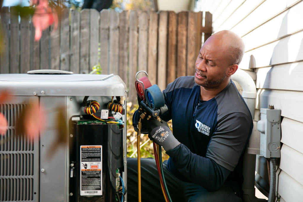 An HVAC technician checking an outdoor air conditioning unit with gauges for Alan Energy Services in Naperville, IL