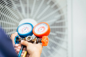 An HVAC technician using manifold gauges to check an AC unit, a service offered by Desert Peaks in Phoenix, AZ.