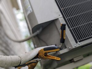 An HVAC technician checking an outdoor AC unit with gauges for Marie Keding Bryant Iowa Heating and Cooling in Ankeny, IA.