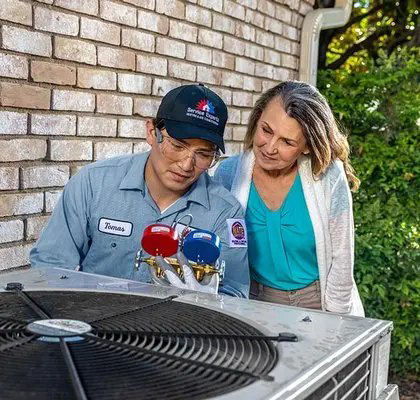An HVAC technician from McElroy Service Experts checking an outdoor AC unit with gauges in Grand Island, NE.