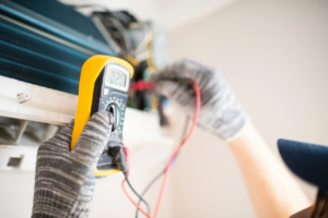 An HVAC technician checking an indoor air conditioning unit with a multimeter for Polaris Heating and Cooling in Columbus, OH.