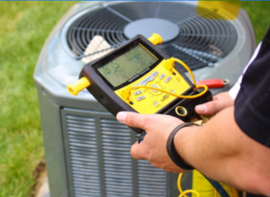 An HVAC technician checking an outdoor AC unit with a digital manifold gauge for Reliance Home Comfort in Hampton, VA.