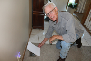 An HVAC technician checking the airflow from an indoor air vent at a home in Wichita, KS, by West Wichita Heating & Air Conditioning.