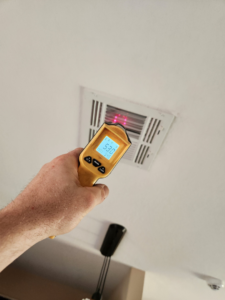 An HVAC technician checking an air vent with an infrared thermometer at Bowers Heating and Air Conditioning in Wichita, KS