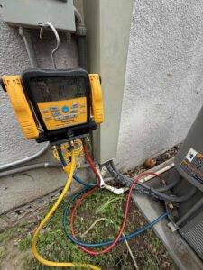 An HVAC technician using a digital manifold gauge set to check an outdoor condenser unit for Affordable Heating and Air in Chatsworth, CA.
