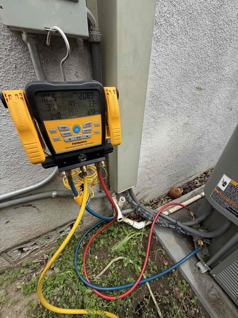 An HVAC technician using a digital manifold gauge set to check an outdoor condenser unit for Affordable Heating and Air in Chatsworth, CA.