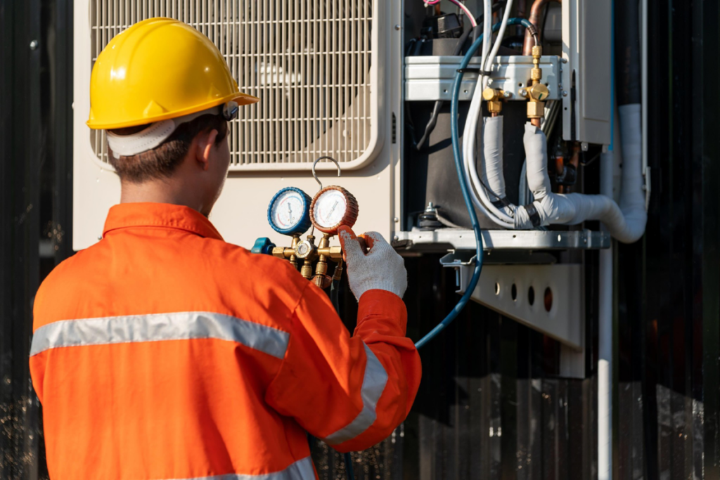 An HVAC technician in a hard hat checking gauges on an outdoor condenser unit for Purair Hawaii in Honolulu, HI.