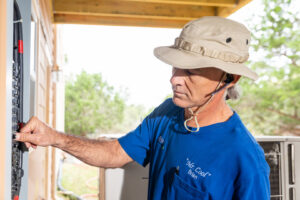 An HVAC technician from Mr. Cool HVAC checking a circuit breaker in an electrical panel during a service call in Cypress, TX.