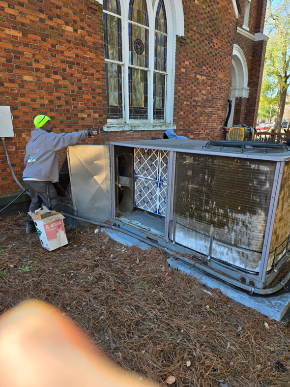 An HVAC technician from Coleman Services inspecting or replacing filters in an outdoor HVAC unit in Columbia, SC, with a refrigerant box nearby.