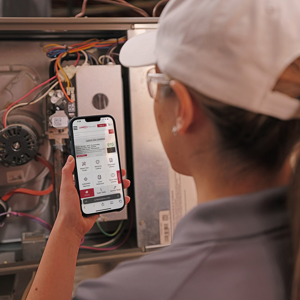 An HVAC technician checking an app on a phone while working on a furnace at Unified Home Solutions in Stamford, CT.