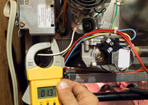 An HVAC technician using a clamp meter to check electrical current on a furnace at Alien Air Conditioning and Heating in Phoenix, AZ.
