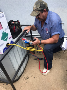 An HVAC technician checking an outdoor AC unit with gauges for Best Air Conditioning & Heating, Co. in Memphis, TN.